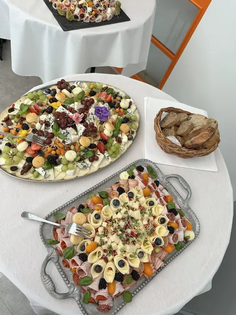 Misy so syrmi a šunkou na okrúhlych stoloch s bielymi obrusmi počas akcie